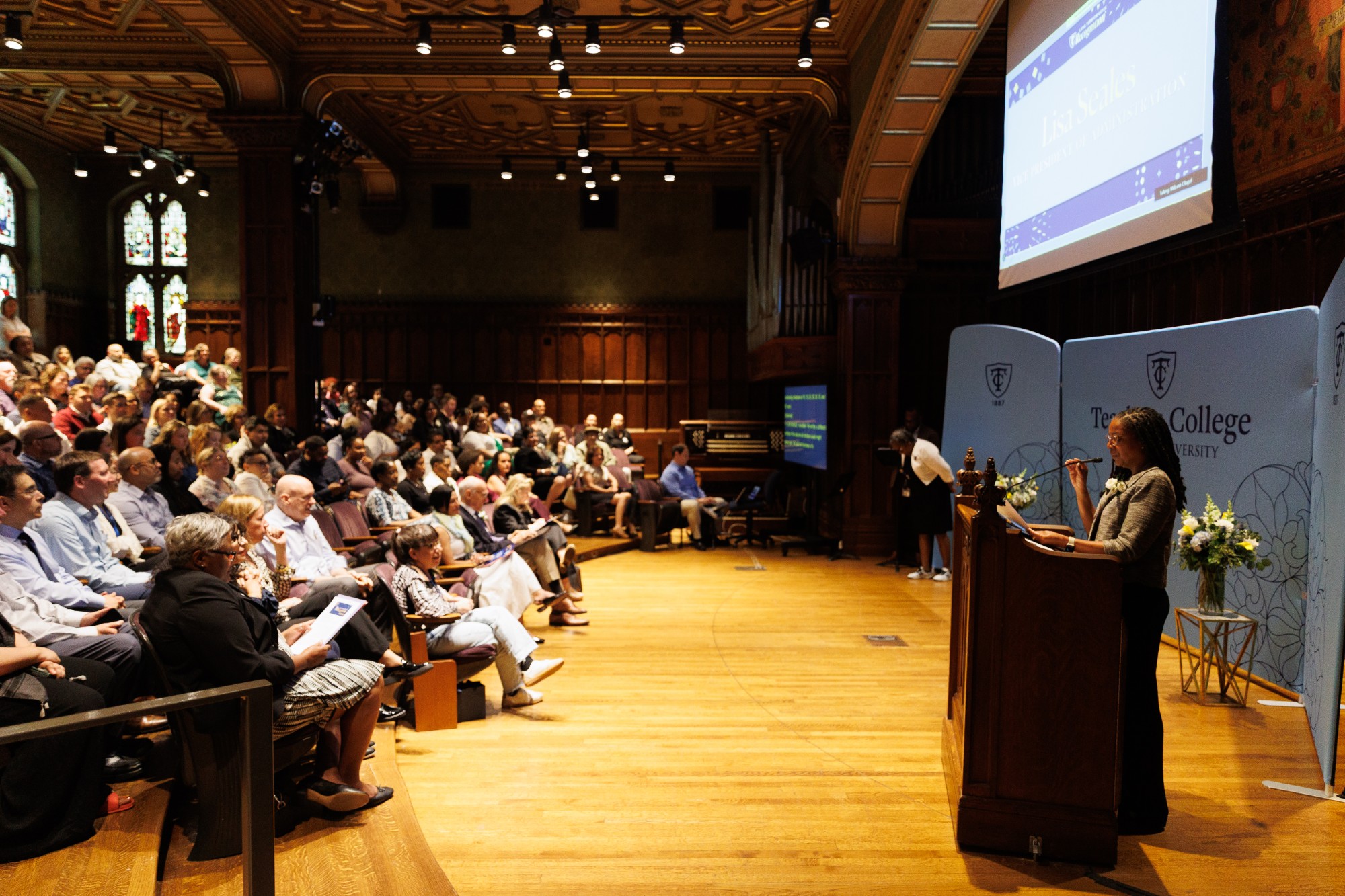 Lisa Seales at the podium in Milbank Chapel with a full seated audience