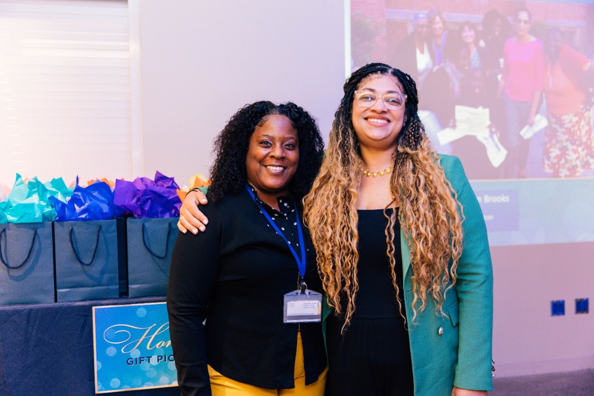 wo people standing with colorful gift bags on a table in the background