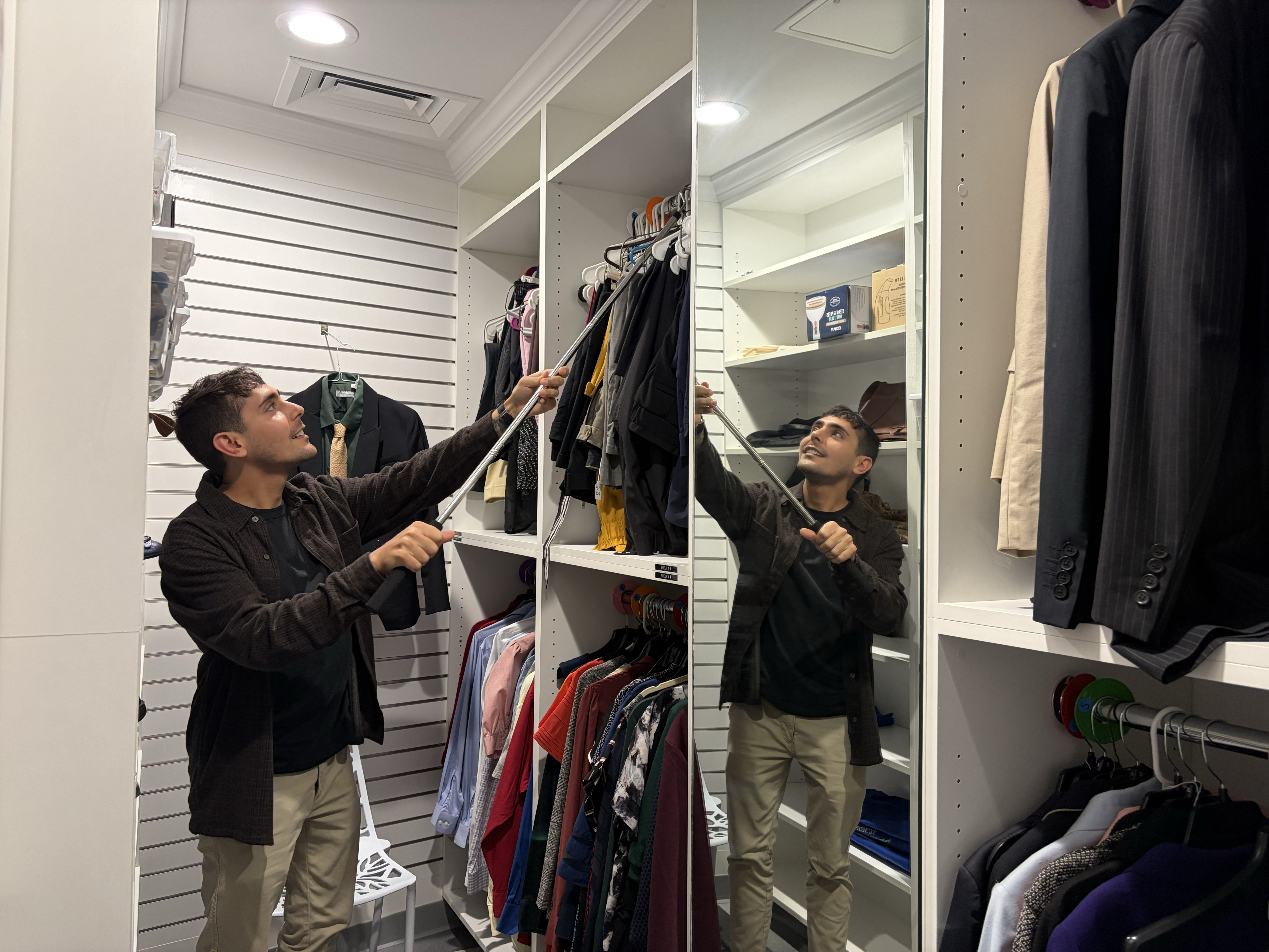 Student worker hangs up clothing in the career closet