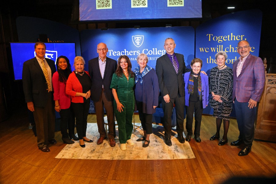 Group of 10 people posing and standing on a stage with TC Reunites signs behind them