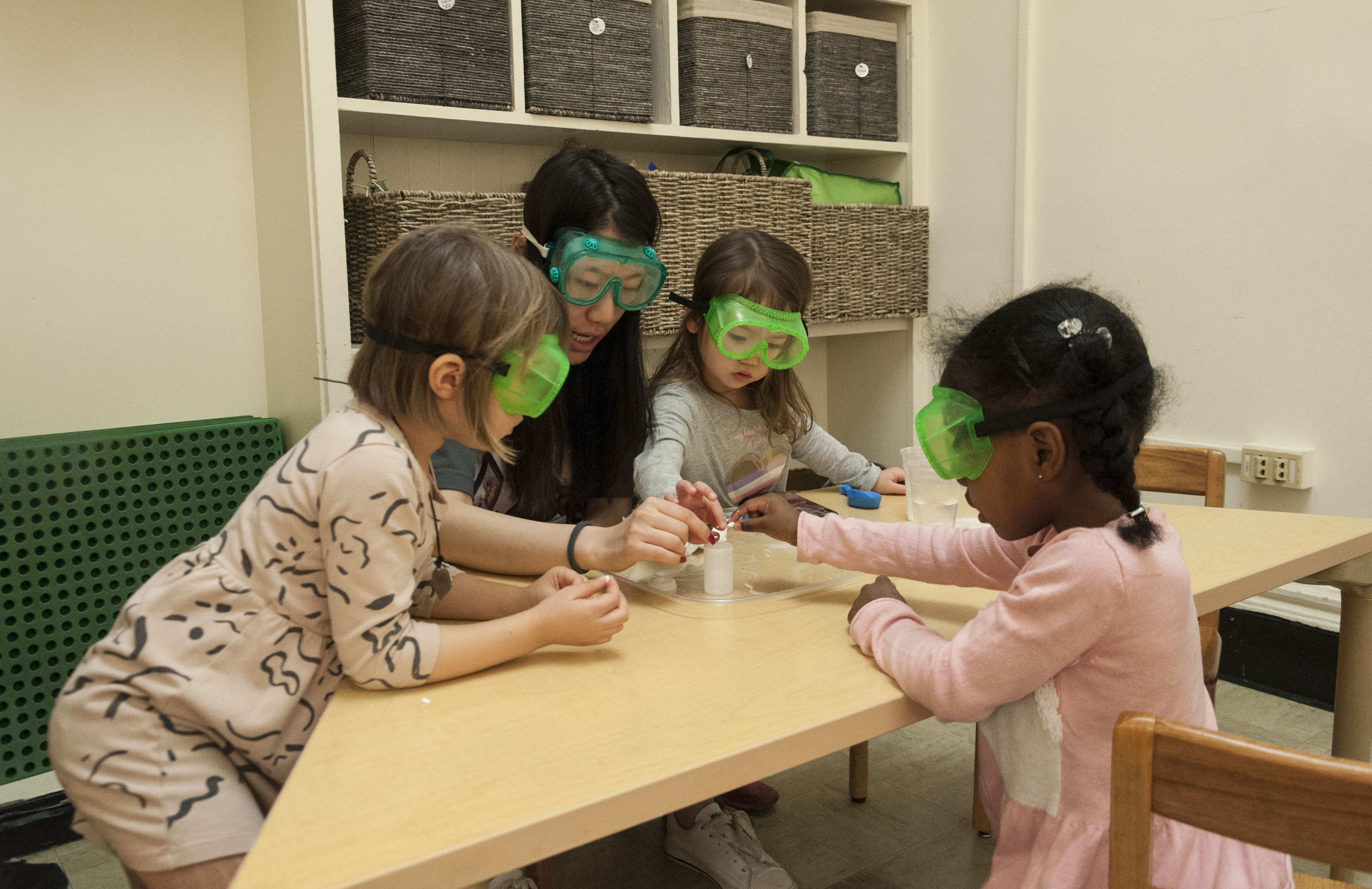 teacher and students with safety goggles on mixing different substances together.