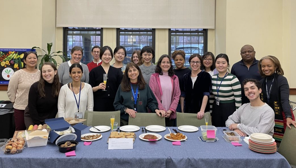 Group of coed nutrition professionals standing together in front of a table with food on it.