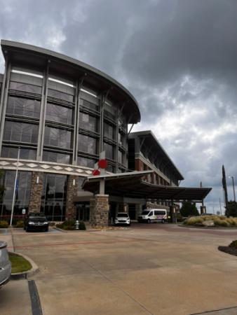 The outside of a large round grey office building is viewed from the parking lot. The building is the Choctaw Nation's headquarters.