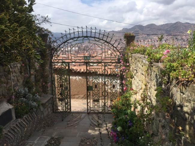 A decorative gate belonging to a private school overlooks the town and mountains of Cusco, Peru