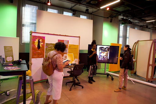 An image of MediaFest attendees at the Groovin' Griot station making conversation and perusing a zine.