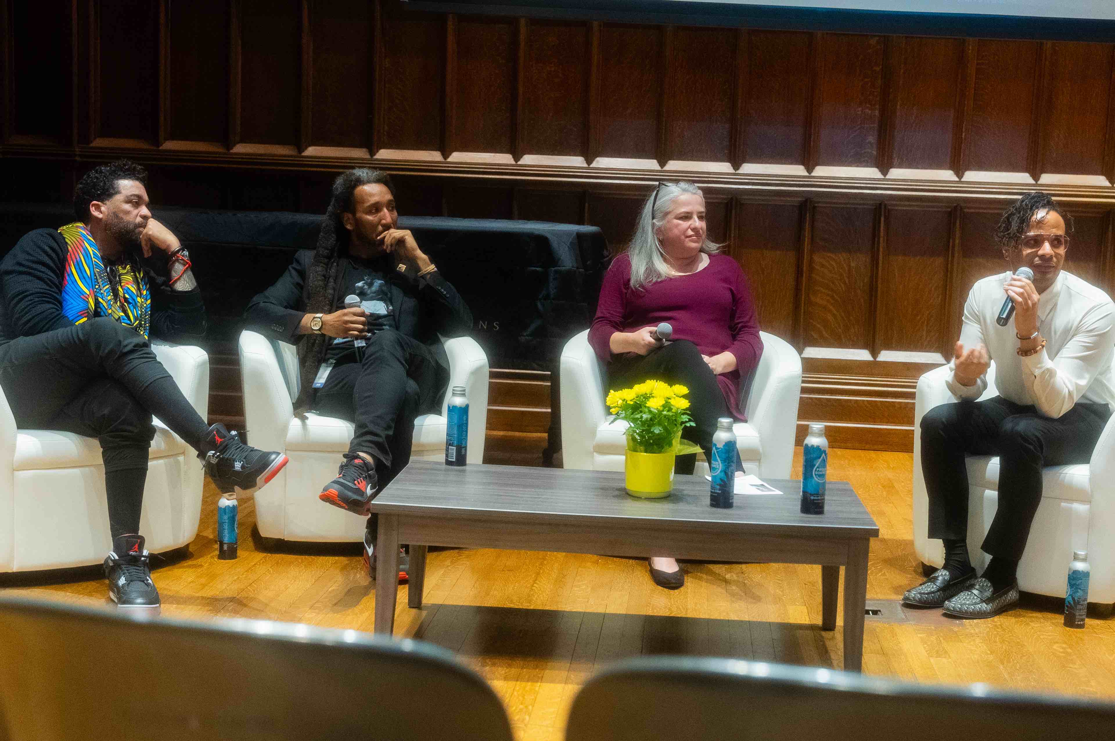 four people sitting in large white chairs have a conversation on a chapel stage