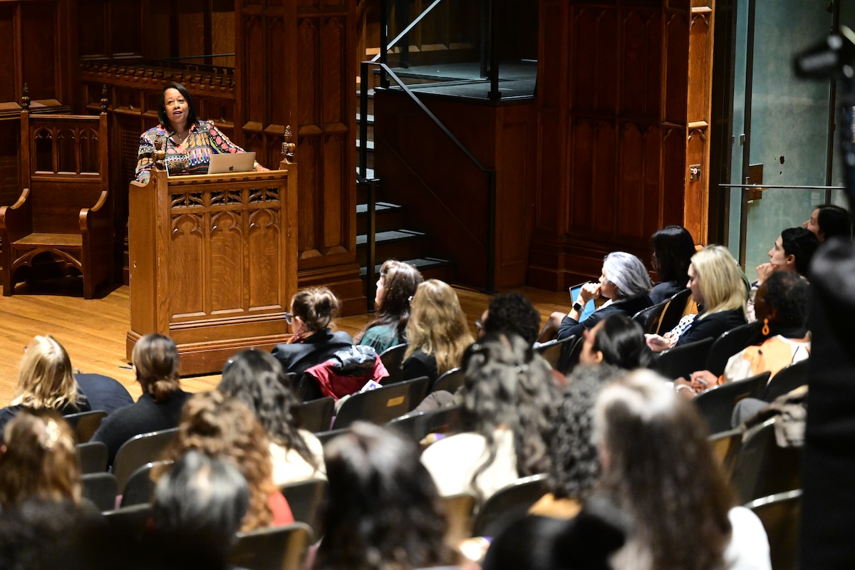 Sonja Cherry-Paul stands at a podium and address an audience