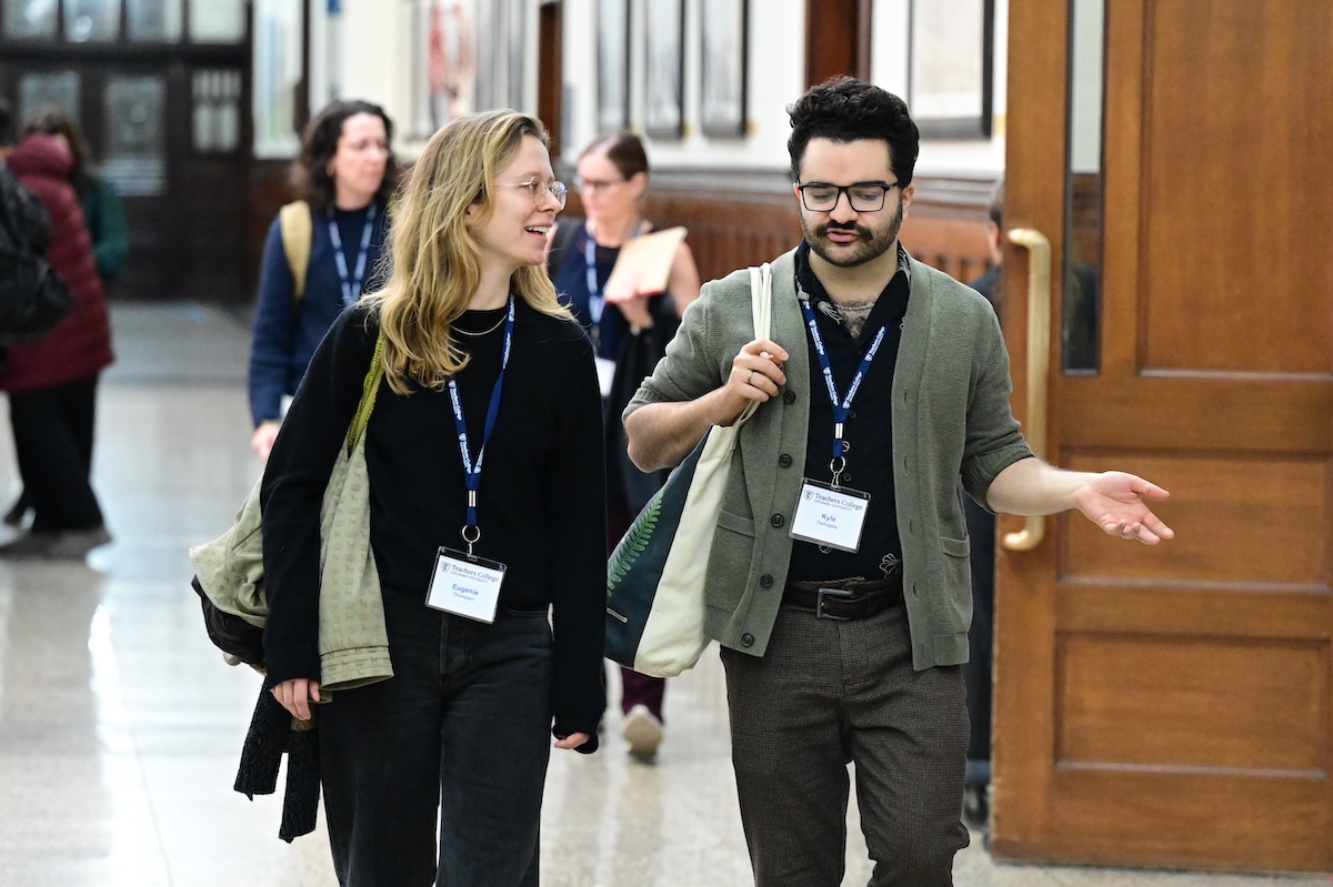 Two people having a conversation while walking down a hallway