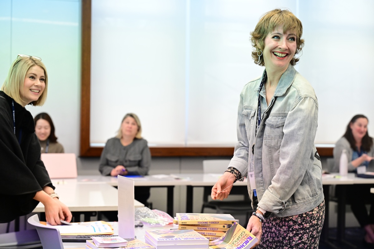 Rebecca Clapp and Kass Minor standing around a table with books on it and smiling