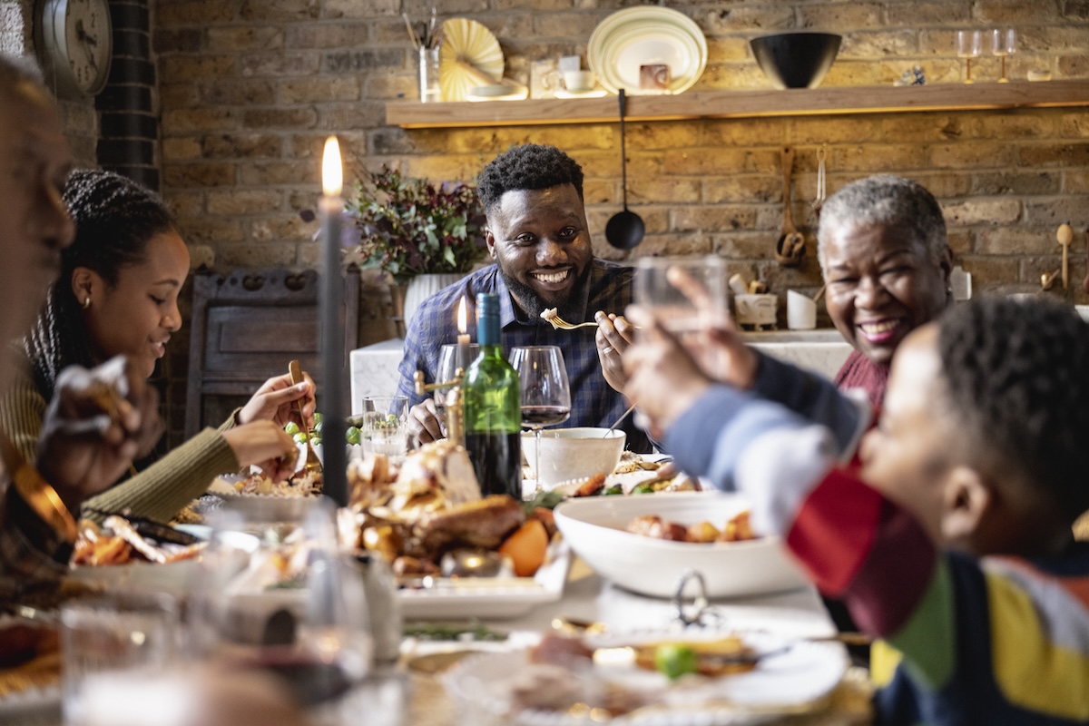 Candid portrait of three generation Black family enjoying roast lunch