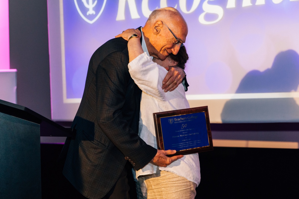 Employee hugging President Bailey while accepting certificate