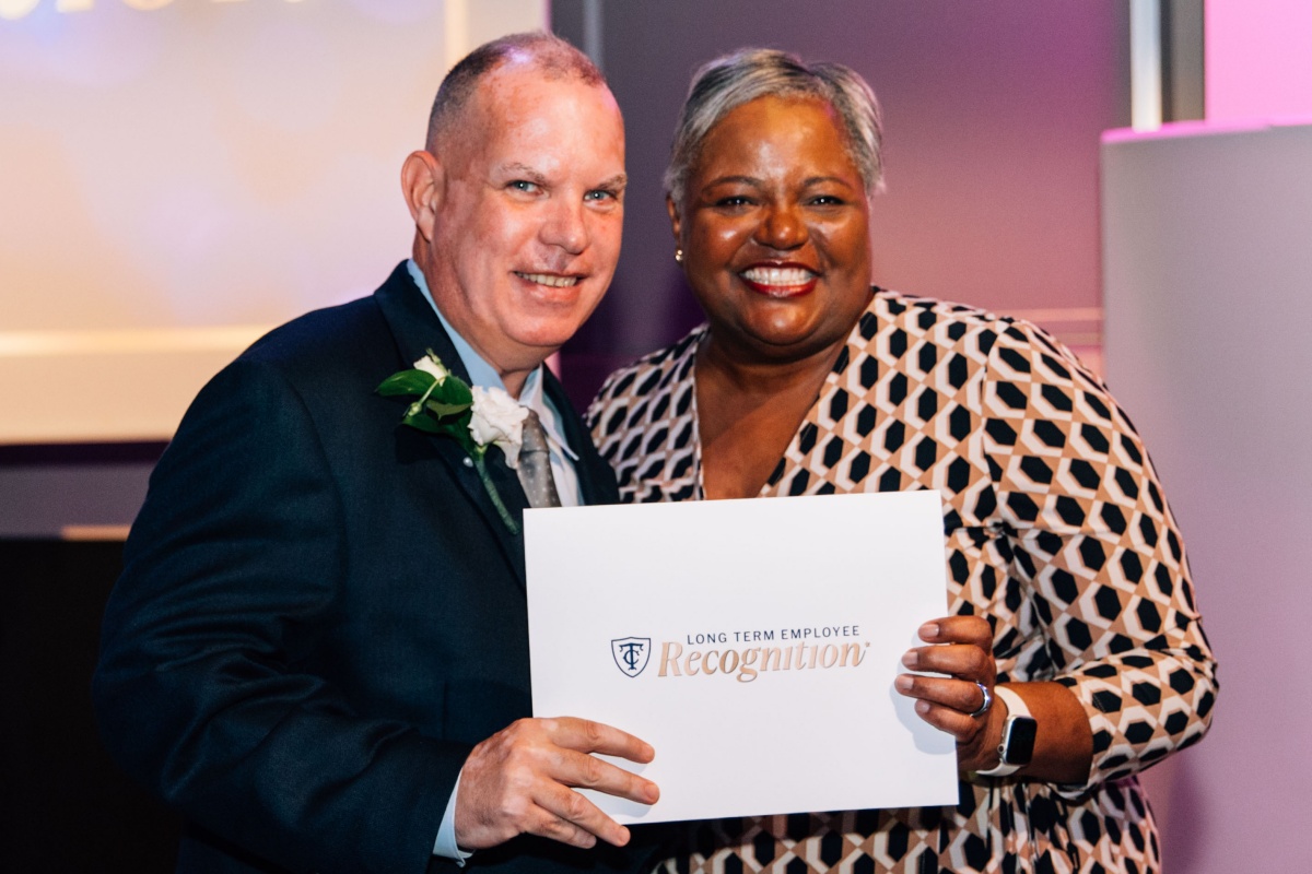 Two employees smiling with certificate