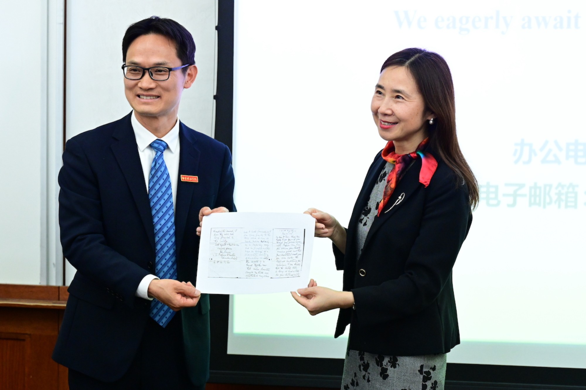 Wenqiu He and Henan Cheng holding a piece of paper