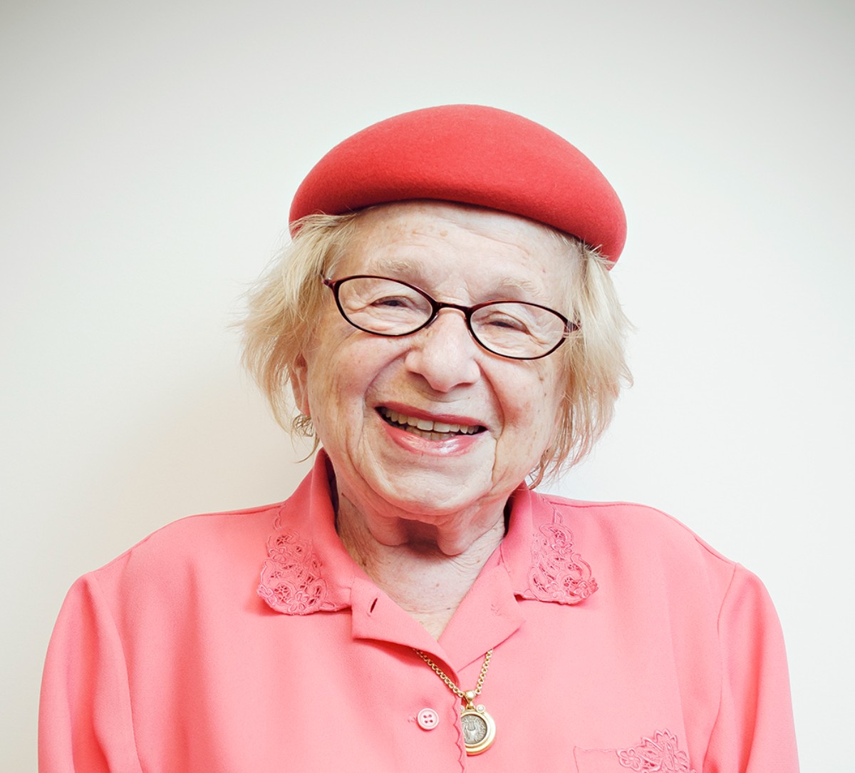 Dr Ruth smiling in a pink hat and pink shirt