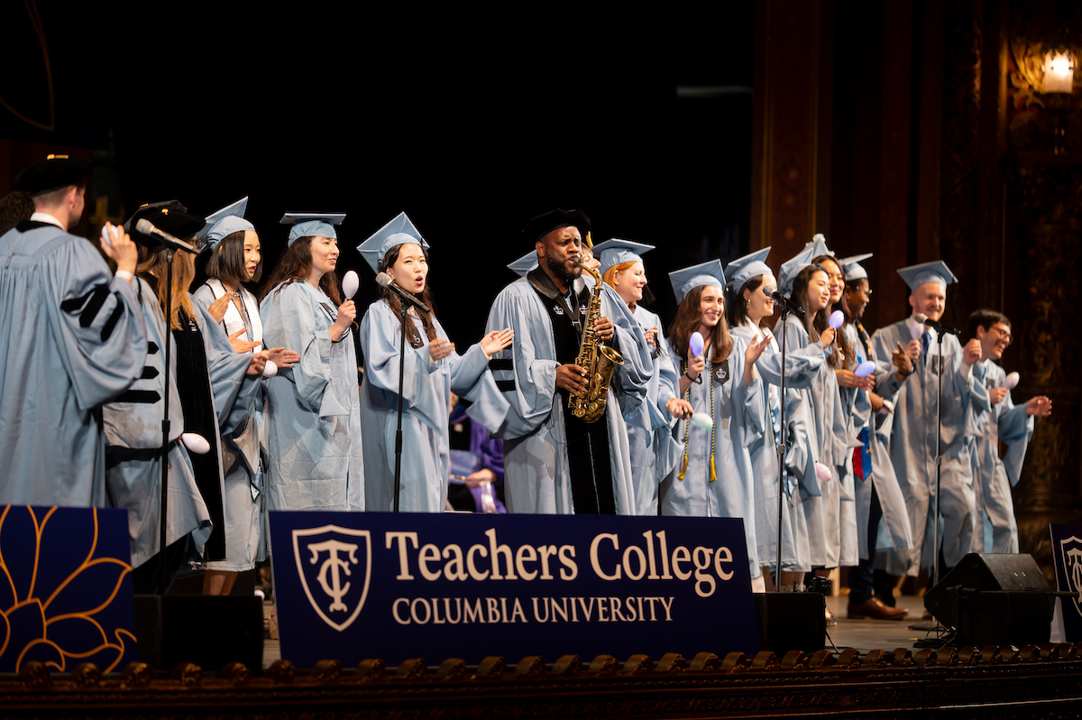 A TC choir accompanied by a saxophone player performs at Convocation 2024 in graduation regalia.