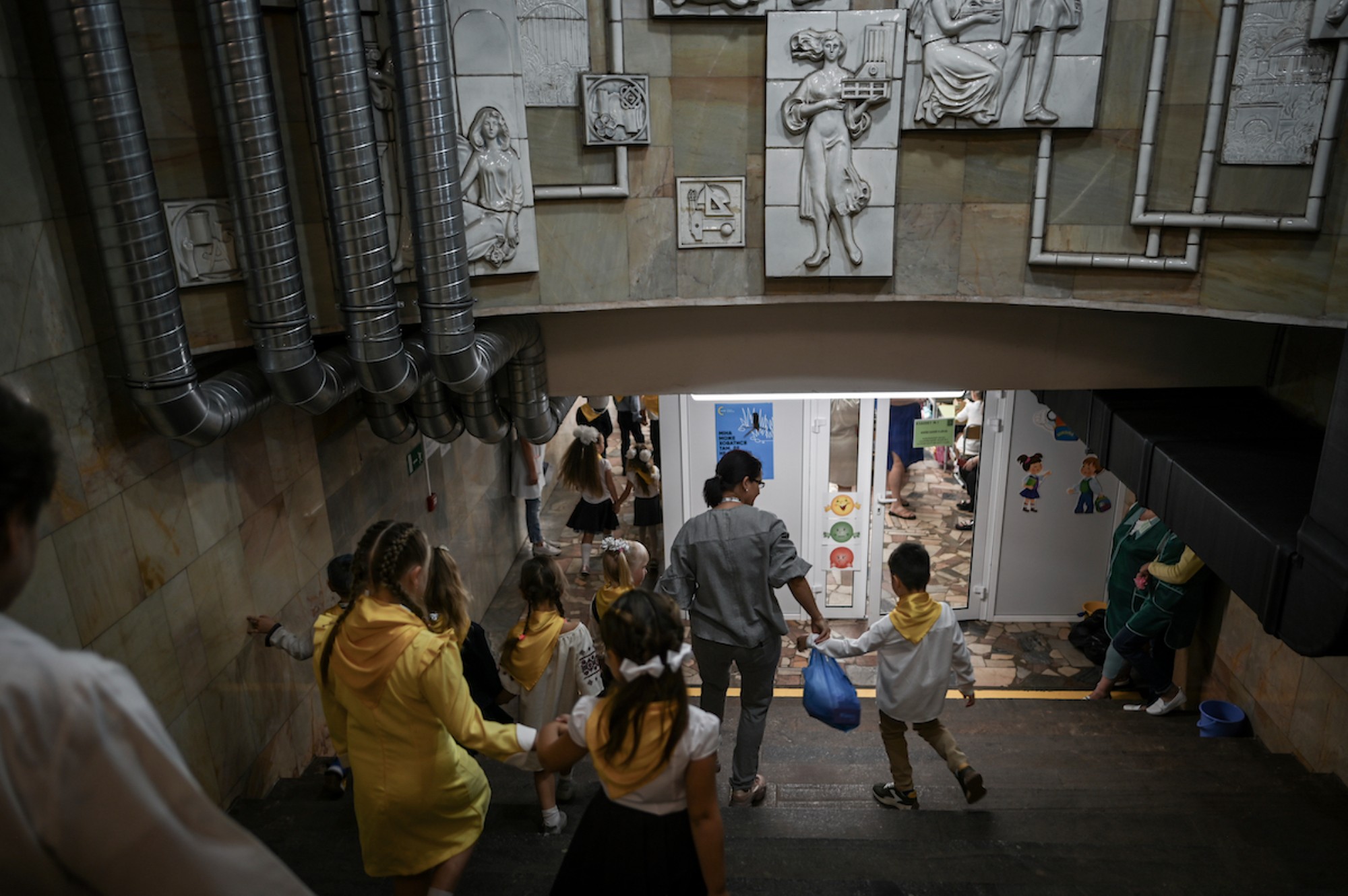 A Ukrainian teacher leads her students back into a classroom in the Universytet Metro station of Kharkiv city