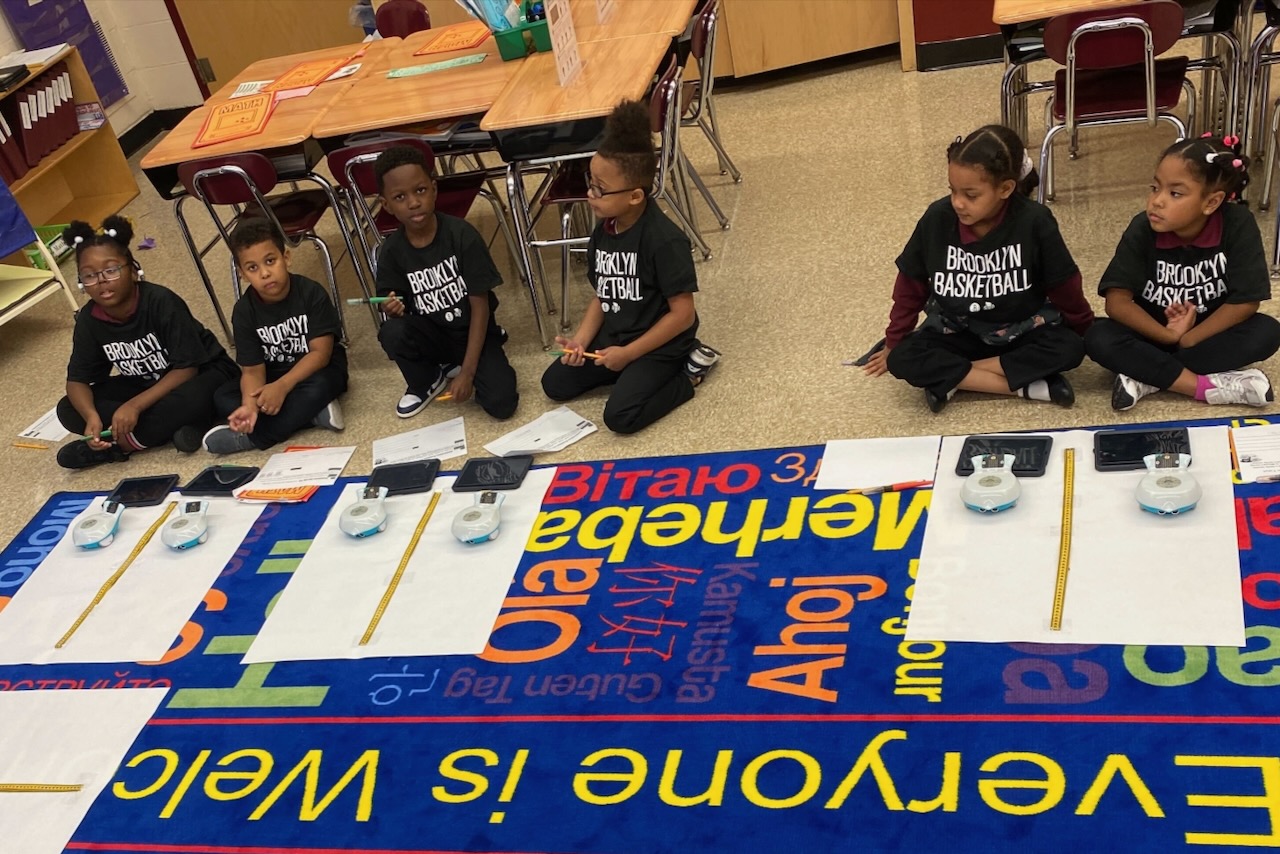 A group of Black children using robots during a math class