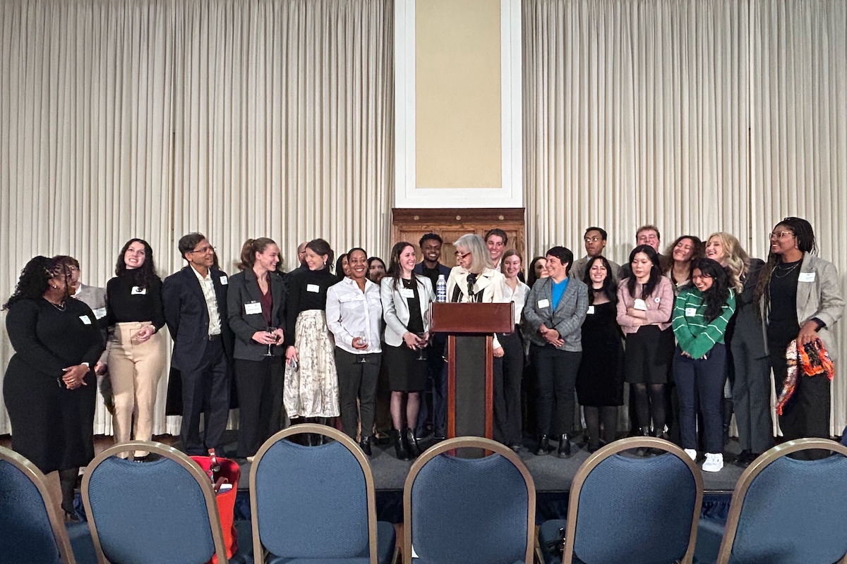 A multiracial group of people posing for a picture on a small stage with a podium