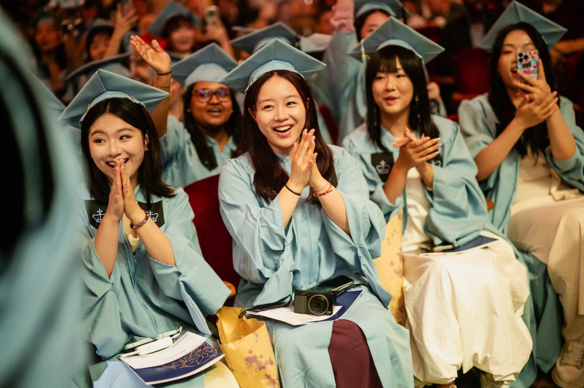 Graduates clap and smile in audience.