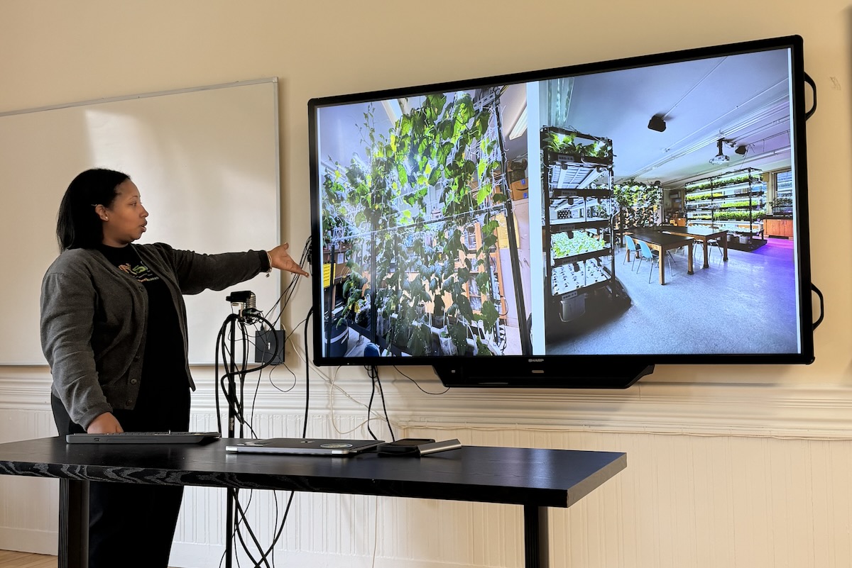 Woman pointing at a screen with pictures of hydroponics labs