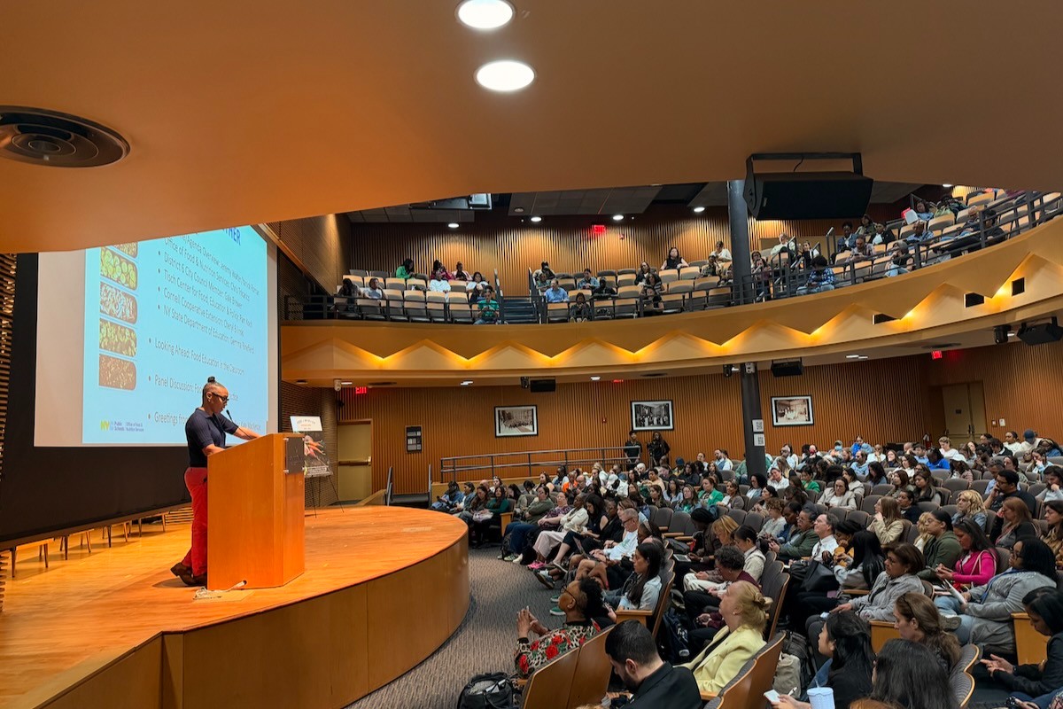 packed audtorium with a speaker at a podium