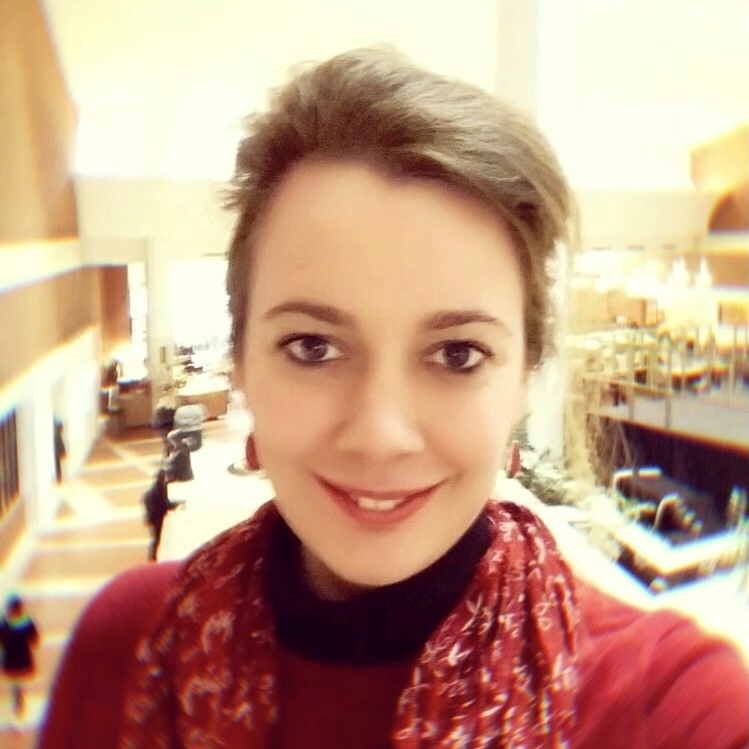 A woman in a red sweater smiles softly at the camera